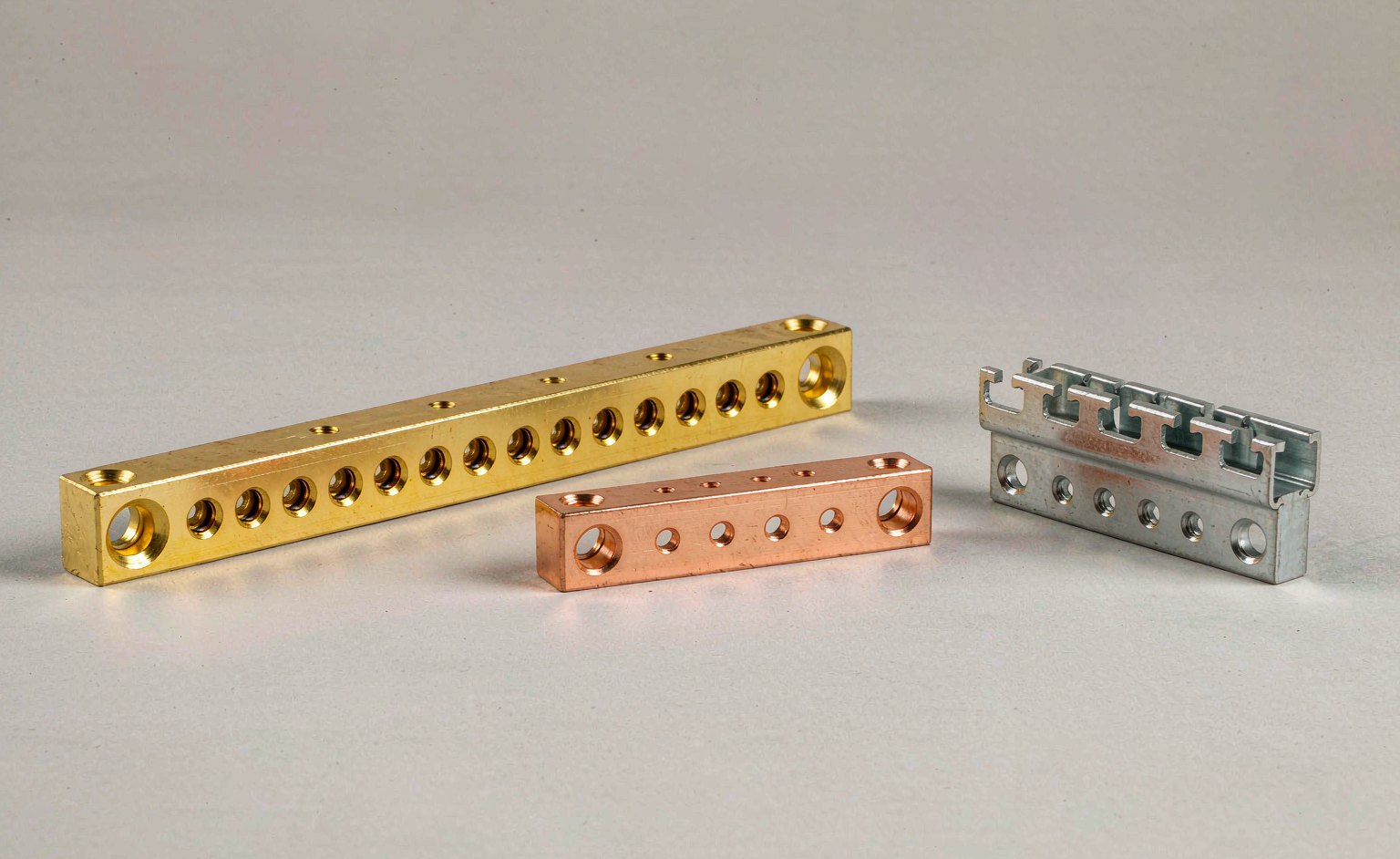 Side by side comparison of a long 15-way panel mount neutral bar, a short 4-way copper bar and a DIN rail clip-on neutral bar showing relative scale